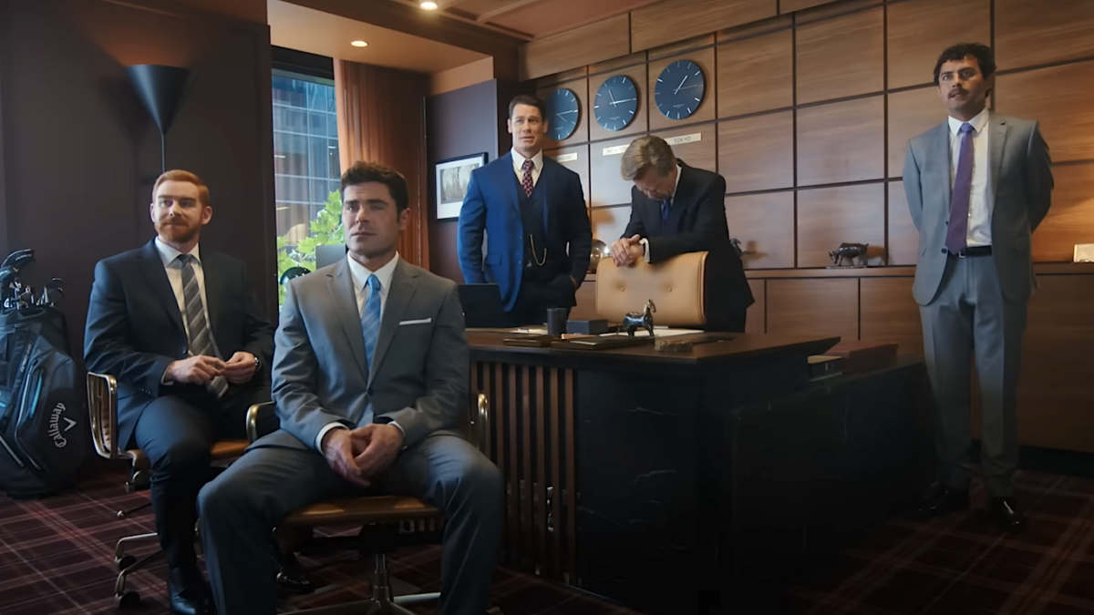 men sitting around an office in a scene from Ricky Stanicki